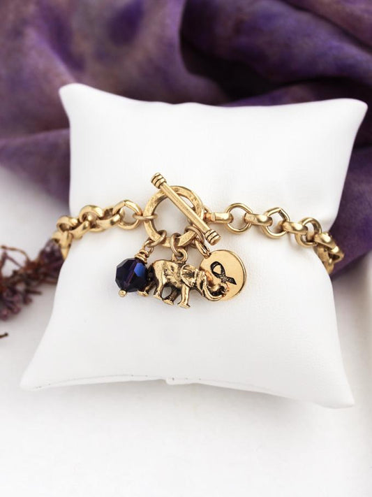 gold toggle alzheimers bracelet with elephant, purple crystal, and memory ribbon