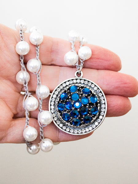 sparkly blue pearl necklace held in hand